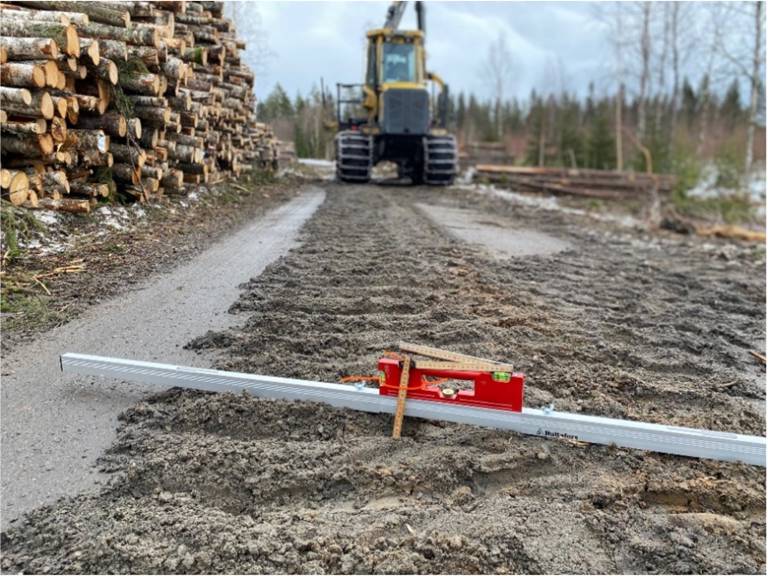 tumstock och vattenpass som visar vägskada